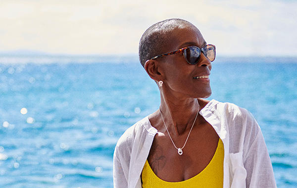 Woman sitting on a yacht in summer clothes, gazing into the distance and smiling. 
