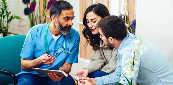 Male doctor discussing a document with a young couple