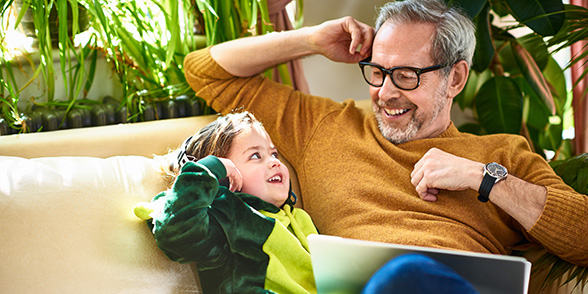Father and daughter laughing together on a sofa