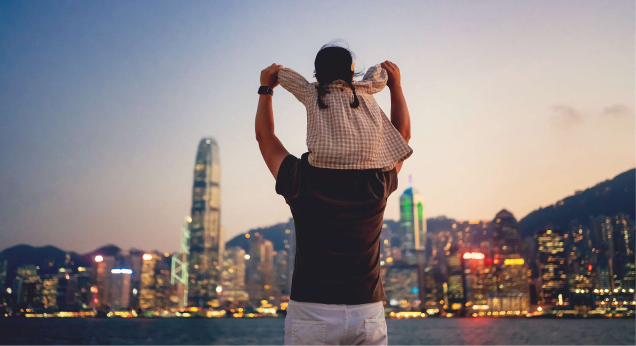 Child sitting on parent's shoulders with city skyline in the background
