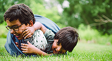 Two children playing together in the grass