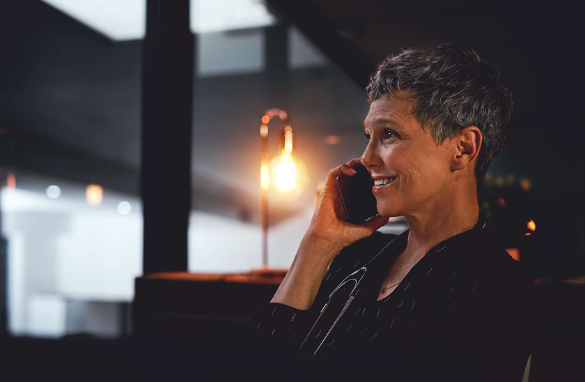 woman smiling while on phone in a dark office
