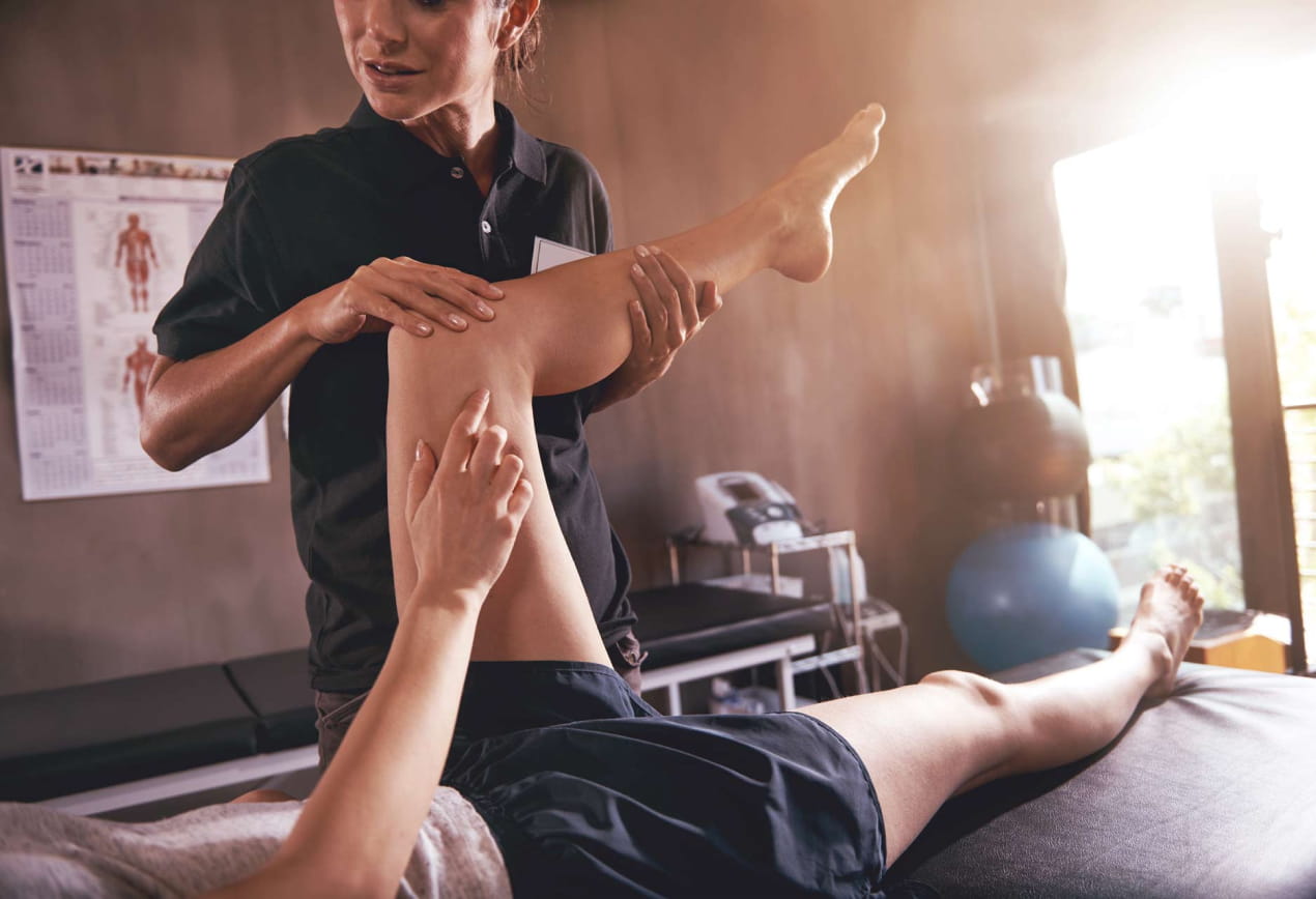 Person receiving physiotherapy from female physiotherapist in treatment room